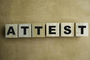 Concept of The wooden Cubes with the word Attest on wooden background. photo