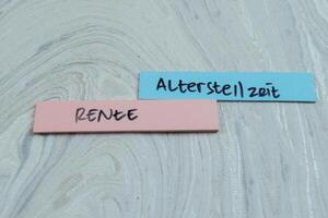 Concept of Altersteilzeit or Rente write on sticky notes isolated on Wooden Table. photo