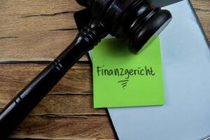 Concept of Finanzgericht in Language Germany write on sticky notes isolated on Wooden Table. photo