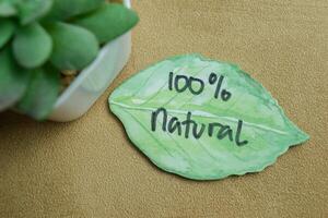 Concept of 100 percent Natural write on sticky notes isolated on Wooden Table. photo