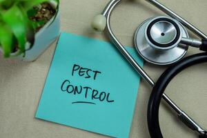 Concept of Pest Control write on sticky notes isolated on Wooden Table. photo