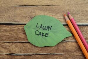 Concept of Lawn Care write on sticky notes isolated on Wooden Table. photo