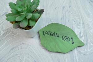 Concept of Vegan write on sticky notes isolated on Wooden Table. photo