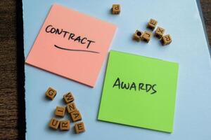 Concept of Contract Awards write on sticky notes isolated on Wooden Table. photo