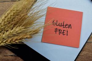 Concept of Gluten Frei in Language Germany write on sticky notes isolated on Wooden Table. photo