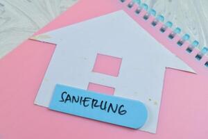 Concept of Sanierung write on sticky notes isolated on Wooden Table. photo