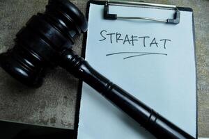 Concept of Learning language - German. Straftat it means crime written on paperwork. German language isolated on Wooden Table. photo