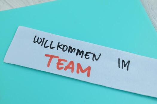 Concept of Willkommen Im Team write on sticky notes isolated on Wooden Table. photo
