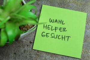 Concept of Learning language - German. Wahl Helfer Gesucht it means Election helper wanted written on sticky notes. German language isolated on Wooden Table. photo