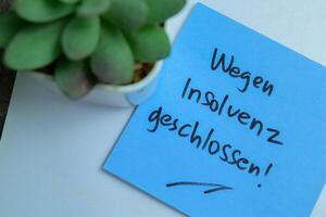 Concept of Learning language - German. Wegen Insolvenz Geschlossen it means Closed due to bankruptcy written on sticky notes. German language isolated on Wooden Table. photo