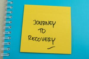 Concept of Journey To Recovery write on sticky notes isolated on Wooden Table. photo