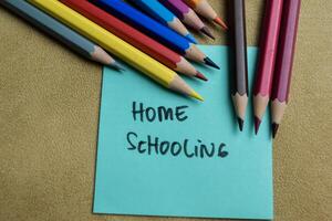 Concept of Home Schooling write on sticky notes isolated on Wooden Table. photo