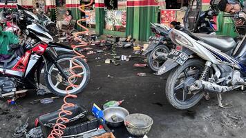 mechanic in overalls making diagnostics of motorbike near toolbox in workshop. Bekasi, Indonesia, April 22, 2024 photo