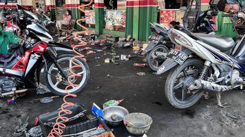 mecánico en mono haciendo diagnósticos de moto cerca caja de herramientas en taller. bekasi, Indonesia, abril 22, 2024 foto