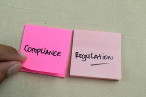 Concept of Compliance Regulation write on sticky notes isolated on Wooden Table. photo