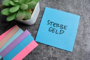 concepto de sterbegeld escribir en pegajoso notas aislado en de madera mesa. foto