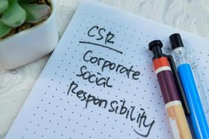 Concept of CSR - Corporate Social Responsibility write on book isolated on Wooden Table. photo