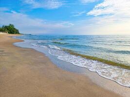 hermosa dorado arena playa amanecer en Mañana Fresco mar ola brisa verano vacaciones. azul cielo y blanco nubes foto