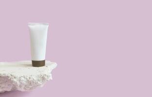 vertical imagen con un blanco vacío botella con un sitio para un marca de productos cosméticos en un Roca podio en un rosado antecedentes de cerca. Copiar espacio. foto