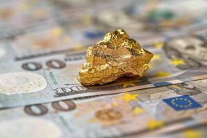 A large gold nugget lies on a table with euro banknotes symbolizing prosperity and wealth photo