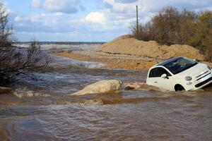 The car was carried away by a strong rain flow of water. photo