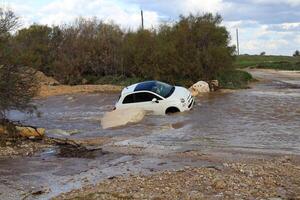 The car was carried away by a strong rain flow of water. photo