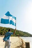 A person holding and waving honduras flag in a beach. Patriotism concept. photo