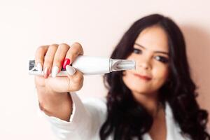 Young Hispanic Woman Holding a Laser For Skin Care. photo