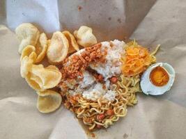 Uduk rice complete with crackers, salted egg, fried noodles, dried tempeh, dried potatoes and fried peanuts photo