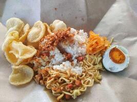 Uduk rice complete with crackers, salted egg, fried noodles, dried tempeh, dried potatoes and fried peanuts photo