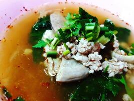 Close up boiled pork blood with minced, entrails and vegetable in pink bowl on table. Asian and hot food. photo