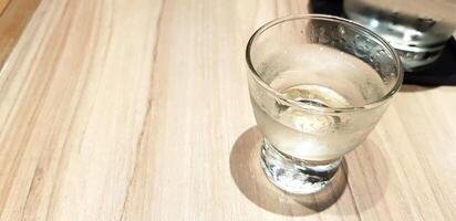 vaso de frío agua en el de madera mesa con Copiar espacio. refresco Bebiendo en woode antecedentes. foto