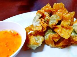 Close up fried dumplings with sweet sauce on white plate. Snack on dish, Asian food style and crispy. photo