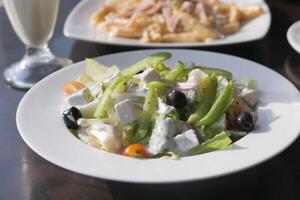 Fresh greek salad with feta cheese, tomato, lettuce, black olives and onion. photo