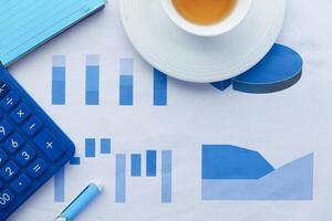 close up of financial charts, calculator and tea on table photo