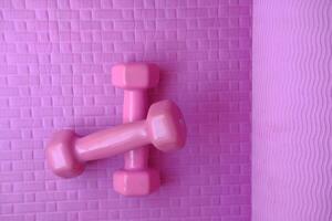 Close up of pink color dumbbell on exercise mat photo