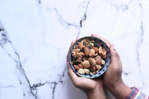 Man hand holding a bowl of Mixed nuts photo