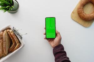 top view of holding smart phone and slice of breads on white background photo