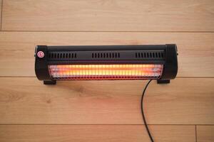 Modern electric infrared heater in living room, closeup photo