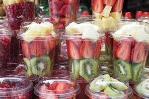 piña, kiwi y fresas en. el plastico envase de venta a tienda foto