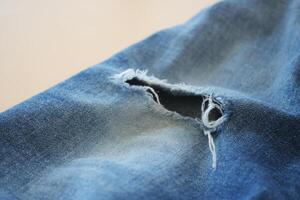 blue jean texture with a hole and ripped threads showing photo