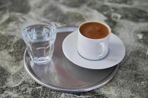 a cup of turkish coffee and glass of water on tiles background photo