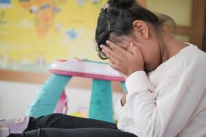 un trastornado niño niña cubrir su cara con mano foto