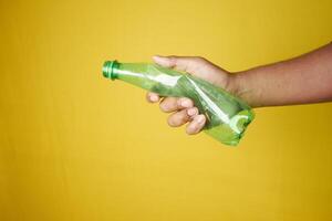 A person is grasping a plastic bottle with their fingers and thumb photo