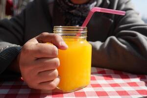 women hand holding a glass of orange juice photo