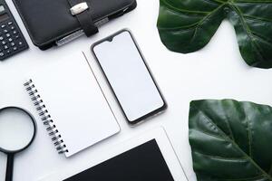 Office desk with laptop, smart phone, coffee cup and supplies, isolated on white background. Top view with copy space, flat lay. photo