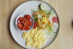 morning breakfast with Scrambled eggs and sausage on a white plate photo