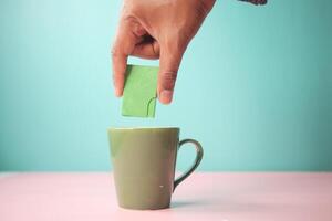 young man putting artificial sweetener in tea, photo