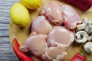 raw breast chicken meat and vegetables on a chopping board photo