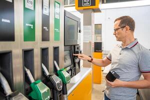 el hombre paga para combustible con un crédito tarjeta en terminal de autoservicio relleno estación en Europa foto